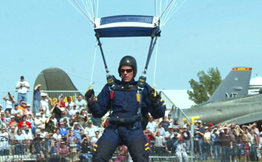 A Navy parachuter lands in a field