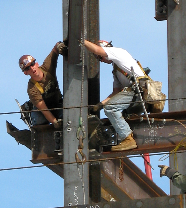 Two construction workers working on an I-Beam.