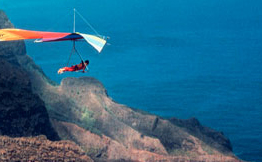 Hang glider flying over mountains towards the ocean