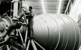 Black and white photo of Saturn V F-1 Engine with a crowd of engineers.