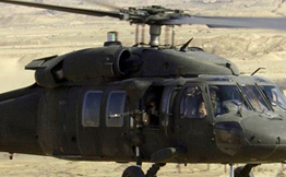 A Blackhawk Helicopter flying over the desert.